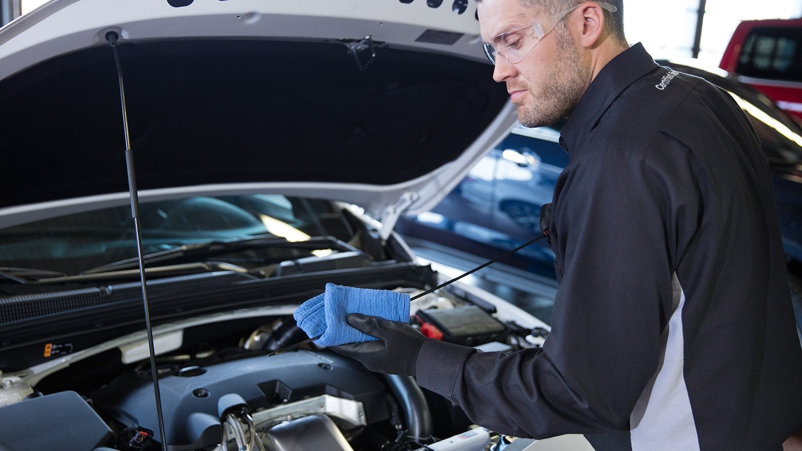 A mechanic checking the oil dipstick under a car hood